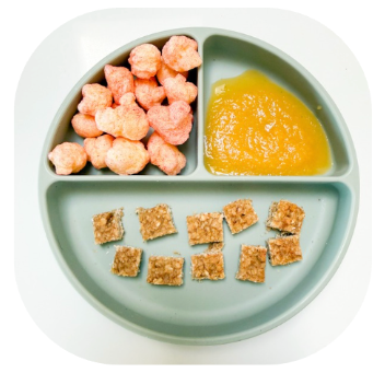 Apple snacks for babies and toddlers | Little Bellies AUS Round green divided plate with three sections: pink puff snacks (top left), orange puree (top right), and square cereal bars (bottom).