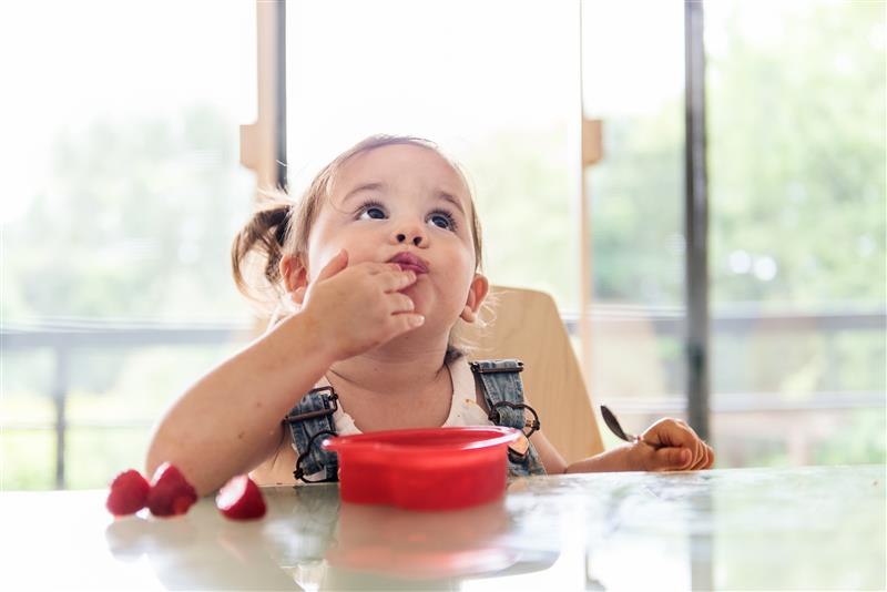 A child sat at a table eating strawberries - Healthy Sugar Habits for Kids.